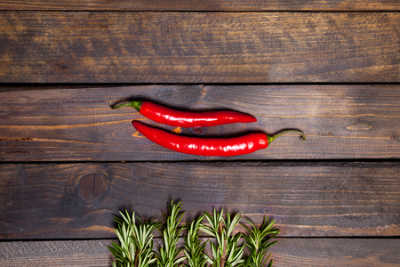 Red chili peppers and green rosemary on wooden backgroundの写真素材