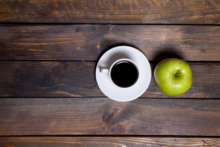 Green fresh apple and coffee in white cup on wooden backgroundの写真素材