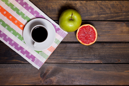 Coffee in white cup with green apple and sliced grapefruit on wooden backgroundの写真素材