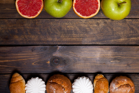 Cake and cut grapefruit and marshmallows and green apple on wooden backgroundの写真素材