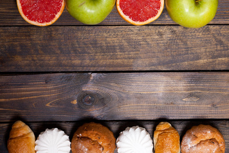 Cake and cut grapefruit and marshmallows and green apple on wooden backgroundの写真素材