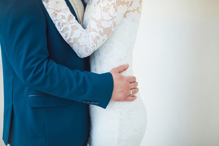 The groom embraces the bride who is holding a bouquet at wedding.の写真素材