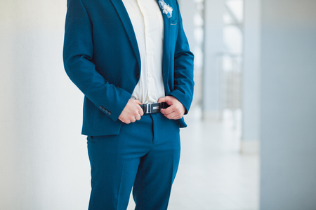 The groom in blue suit holds his hands on the strap.の写真素材