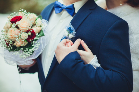 The bridegroom holds wedding bouquet, and the bride hugs him from behind.の写真素材