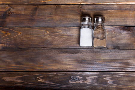 Two transparent cans of salt and pepper shaker on wooden background.の写真素材