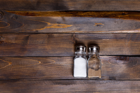 Two transparent cans of salt and pepper shaker on wooden background.の写真素材