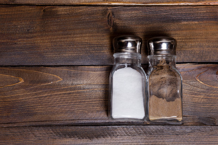 Two transparent cans of salt and pepper shaker on wooden background.の写真素材