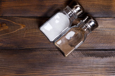 Two transparent cans of salt and pepper shaker on wooden background.の写真素材