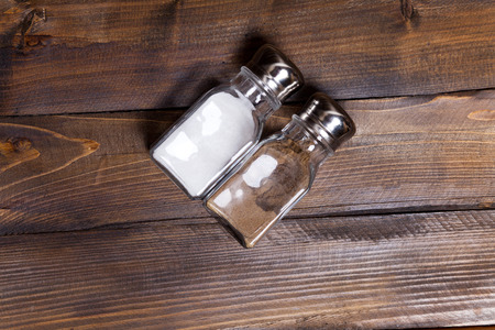Two transparent cans of salt and pepper shaker on wooden background.の写真素材