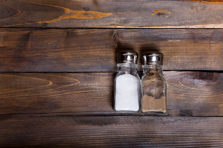 Two transparent cans of salt and pepper shaker on wooden background.の写真素材