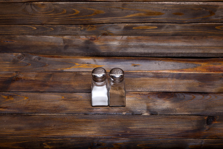 Two transparent cans of salt and pepper shaker on wooden background.の写真素材