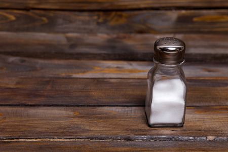 Transparent jar of shaker with salt on wooden background.の写真素材
