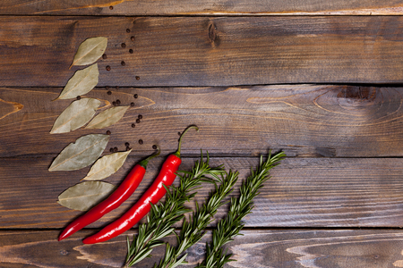 Red chili pepper and rosemary sprigs with laurel leaves on wooden background.の写真素材