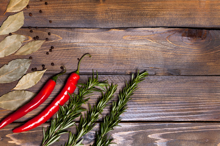 Red chili pepper and rosemary sprigs with laurel leaves on wooden background.の写真素材