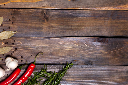 Red chili pepper and rosemary sprigs with laurel leaves and white garlic heads on wooden background.の写真素材