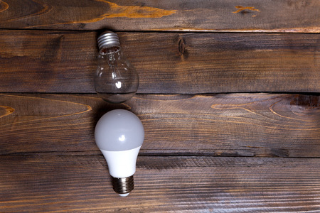 Two light bulbs. LED white and ordinary incandescent lamp on wooden background. Top view.の写真素材