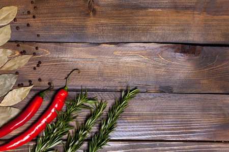 Red chili pepper and rosemary sprigs with laurel leaves on wooden background.の写真素材