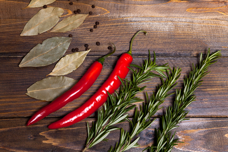 Red chili pepper and rosemary sprigs with laurel leaves on wooden background.の写真素材