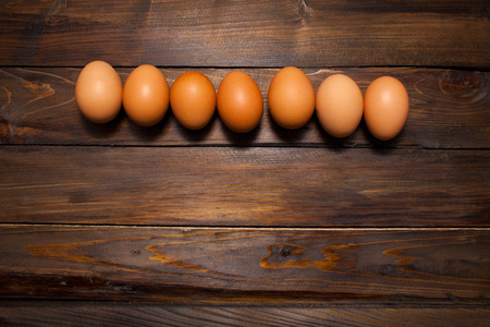 Closed, fresh chicken eggs on a natural wooden background.の写真素材