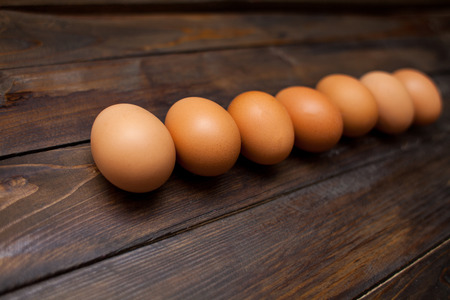 Closed, fresh chicken eggs on a natural wooden background.の写真素材