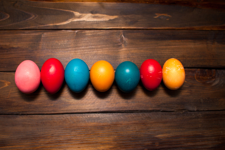 Closed, colored in different bright colors chicken eggs for the holiday Easter on natural wooden background.の写真素材