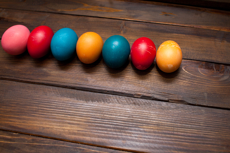 Closed, colored in different bright colors chicken eggs for the holiday Easter on natural wooden background.の写真素材