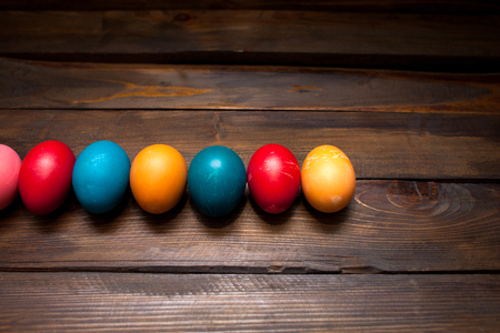 Closed, colored in different bright colors chicken eggs for the holiday Easter on natural wooden background.の写真素材