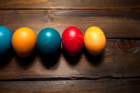 Closed, colored in different bright colors chicken eggs for the holiday Easter on natural wooden background.の写真素材