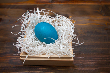 Blue chicken, painted egg for the Easter holiday in a box on a wooden weathering background.の写真素材