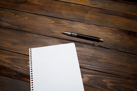 Pen with white sheet of paper in box on wooden background. Top view with copy space.の写真素材