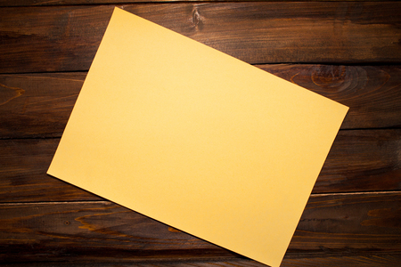 Orange sheet of A4 paper on wooden background. Top view with copy space.の写真素材