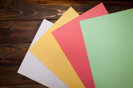 Colored A4 sheets on wooden background. Top view with copy space.の写真素材
