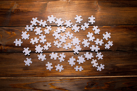 White puzzles from a mosaic on wooden background. Top view.の写真素材