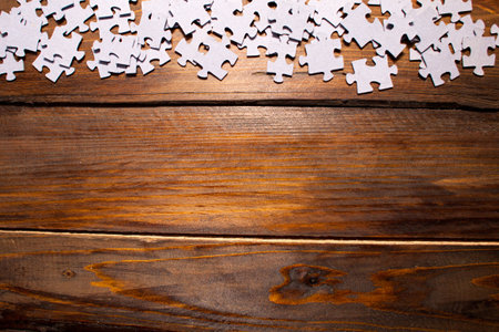White puzzles from a mosaic on wooden background. Top view.の写真素材