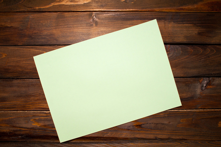 Yellow sheet of A4 paper on wooden background. Top view with copy space.の写真素材