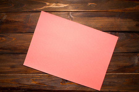Pink sheet of A4 paper on wooden background. Top view with copy space.の写真素材