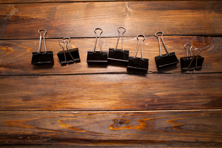 Black clerical paper clips on wooden background.の写真素材