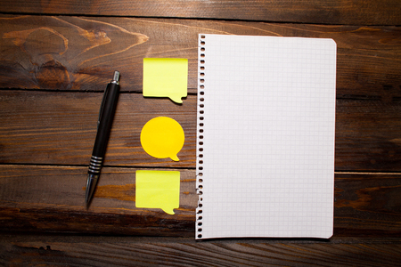 Yellow bright stickers in the form of messages with sheet paper and handle on wooden background. Top view.の写真素材