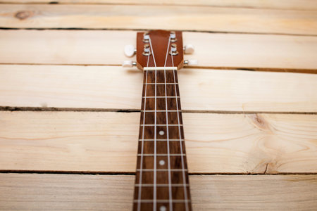 Hawaiian four-stringed guitar ukulele close-up frets on wooden background.の写真素材