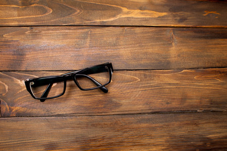 Glasses in black vintage frame on wooden background, table. View from above.の写真素材
