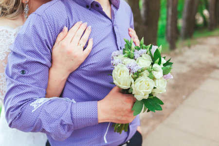 The groom embraces the bride who is holding a bouquet at wedding.の写真素材