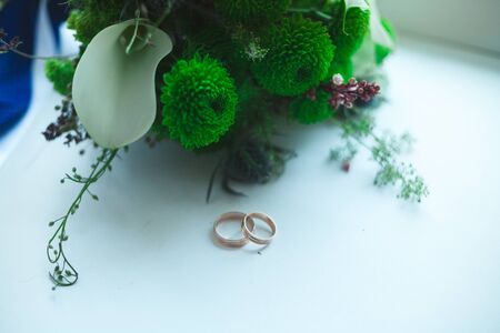 Beautiful bridal bouquet of a bride with gold rings on a white background.の写真素材