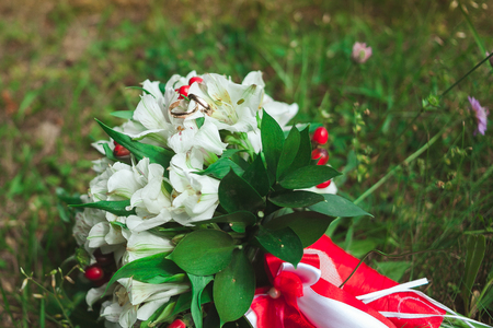 Beautiful golden wedding rings with wedding bouquet of bride on green grass in summer close-up.の写真素材