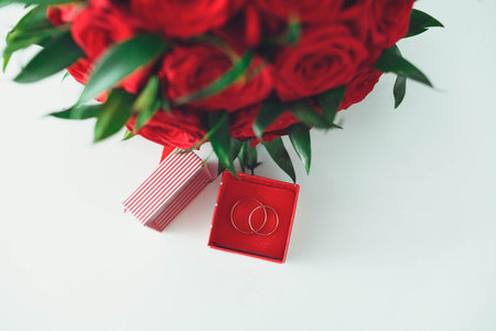 Golden wedding rings in a box with a bouquet of the bride from beautiful flowers.
