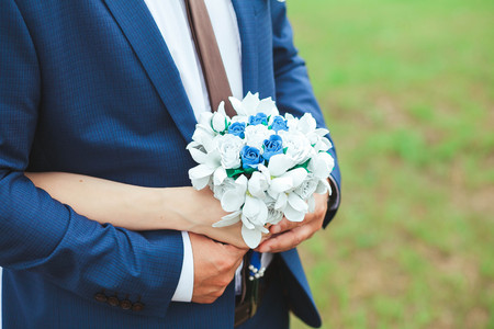 The groom embraces the bride who is holding a bouquet at wedding.の写真素材