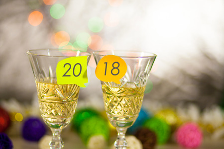 Two glasses with champagne on a table with stickers and an inscription 2018. New Year's bright blurred background.の写真素材