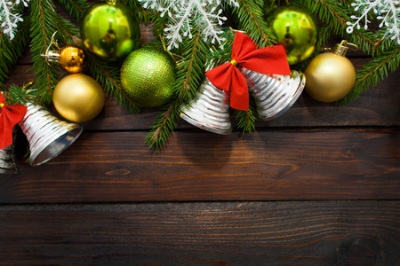 Green living spruce branches on a dark wooden background. New Year background with beautiful balls and white snow and bells. Top view.の写真素材