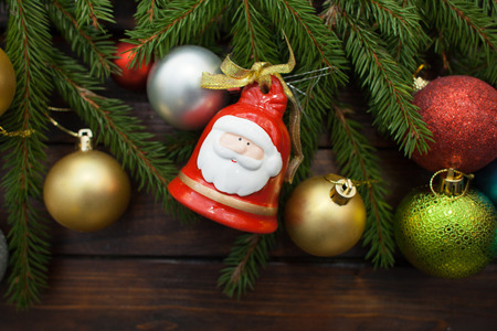 Green living spruce branches on a dark wooden background. New Year background with multi-colored balloons and bells in the idea of Santa Claus. Top view.の写真素材