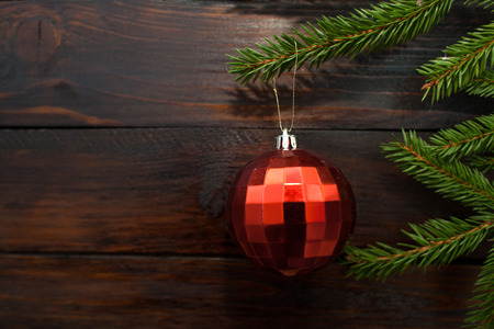 Green Christmas tree branches on a dark wooden background. New Year background with a red glass ball. Top view.の写真素材