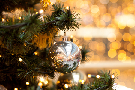 Christmas decorations on green spruce. Symbols of the new year balls and garlands on a blurred yellow background, bokeh.の写真素材